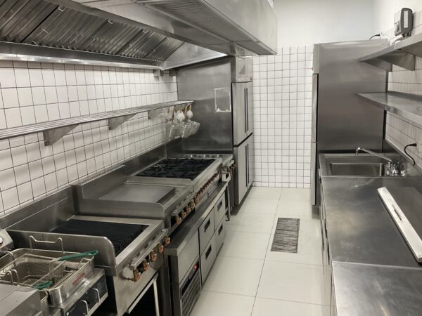 modern restaurant kitchen with two fridges, ovens and hobs