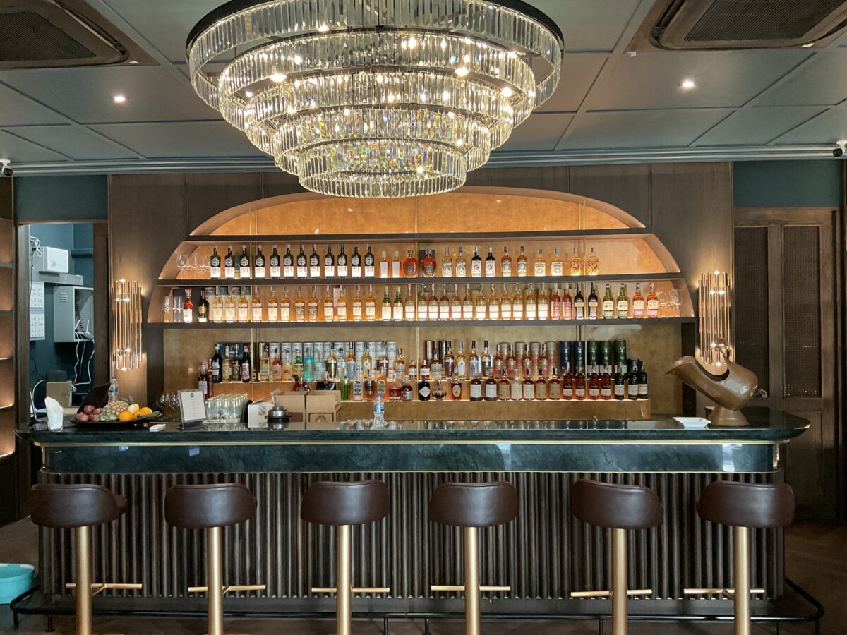 A front view of the renovated Phill Collection bar featuring a chandelier and a stylish bar stool.