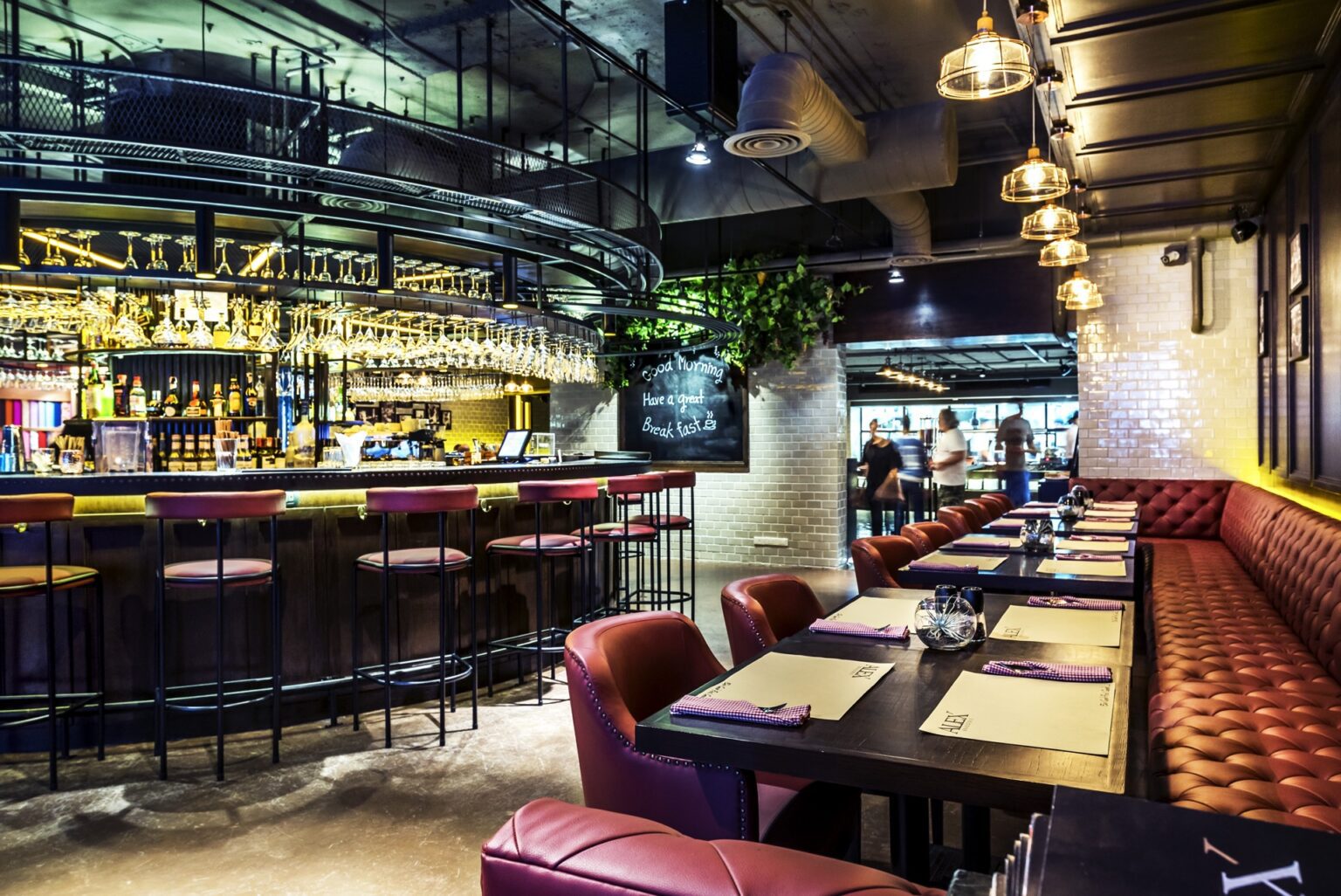 Interior of a rustic restaurant featuring red leather booths and a fully renovated central bar, creating a cozy atmosphere.