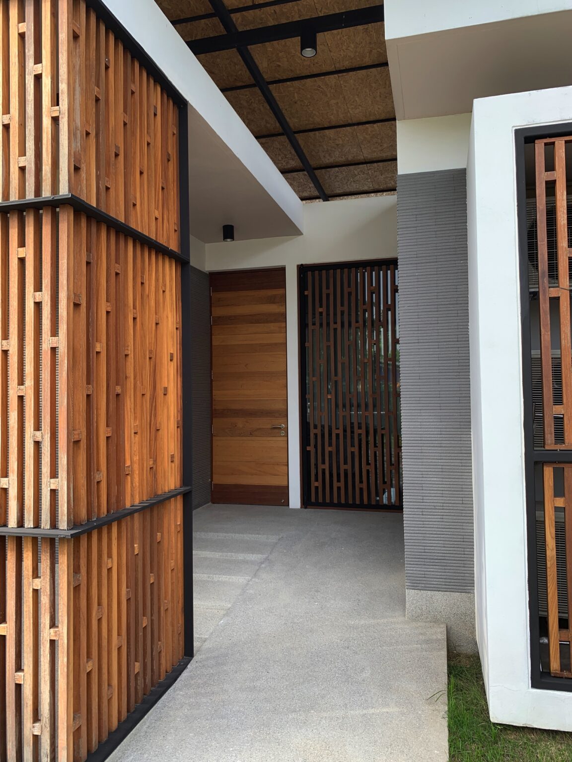 A wooden door framed by a wooden wall, representing the entrance to the Eden Thai villa.