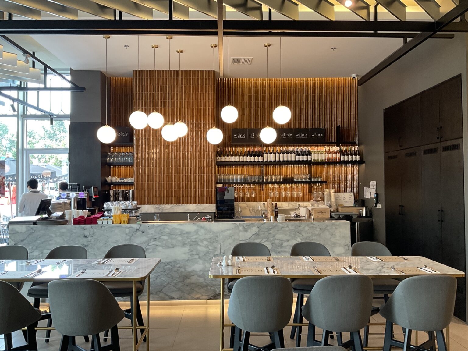 Front view of Wine Connection restaurant showcasing a marble counter, elegant chairs, and organized tables for a delightful dining experience