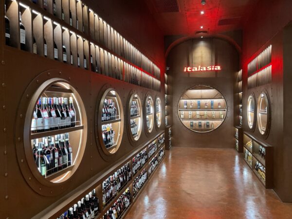 A renovated 'italasia' wine shop featuring a long row of wine bottles elegantly displayed on wooden shelves.