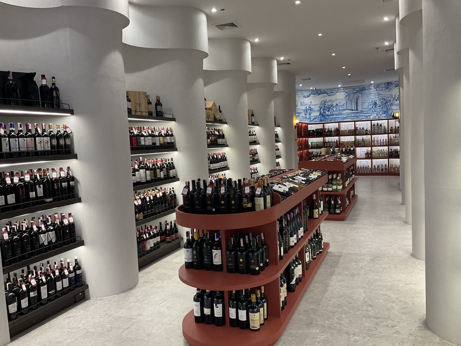 A renovated white wine cellar featuring shelves filled with bottles and adorned with a beautiful fresco.