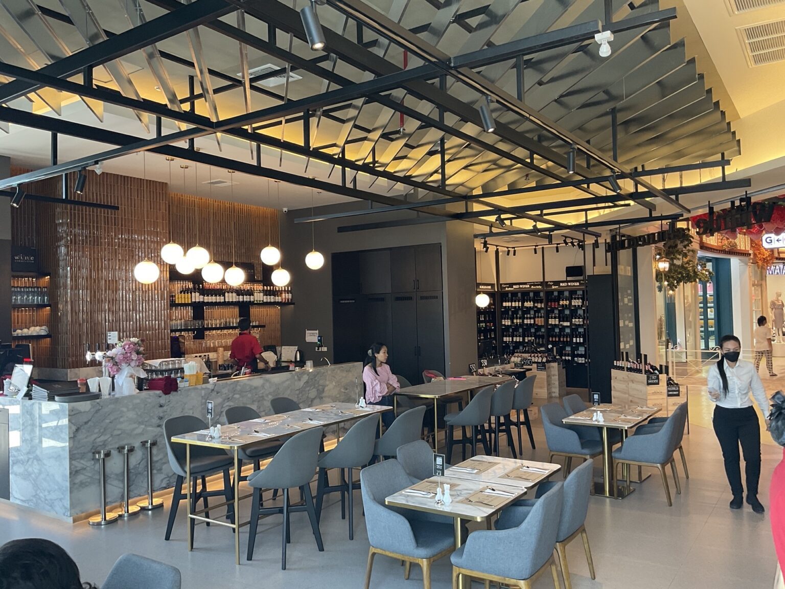 A renovated 'Wine Connection' restaurant featuring tables and chairs arranged in the center, complemented by a stylish bar.