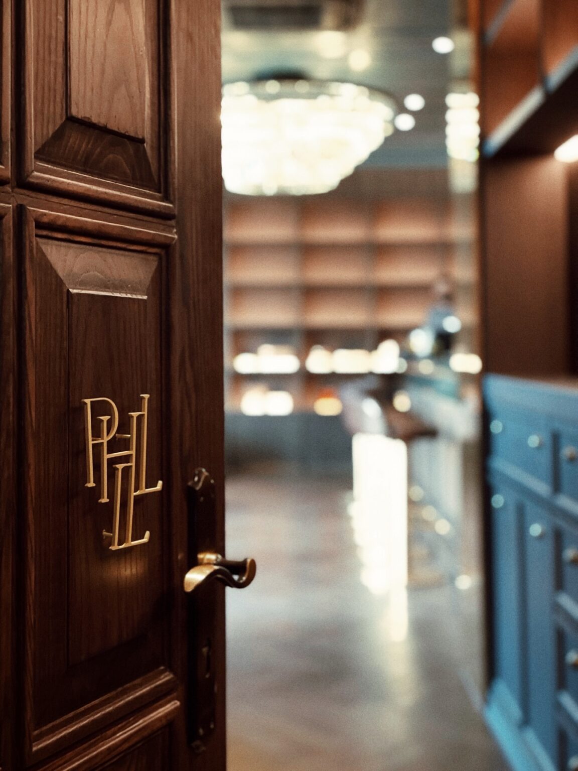 A wooden door featuring a gold logo, serving as the entrance to a Phill Collection salon.