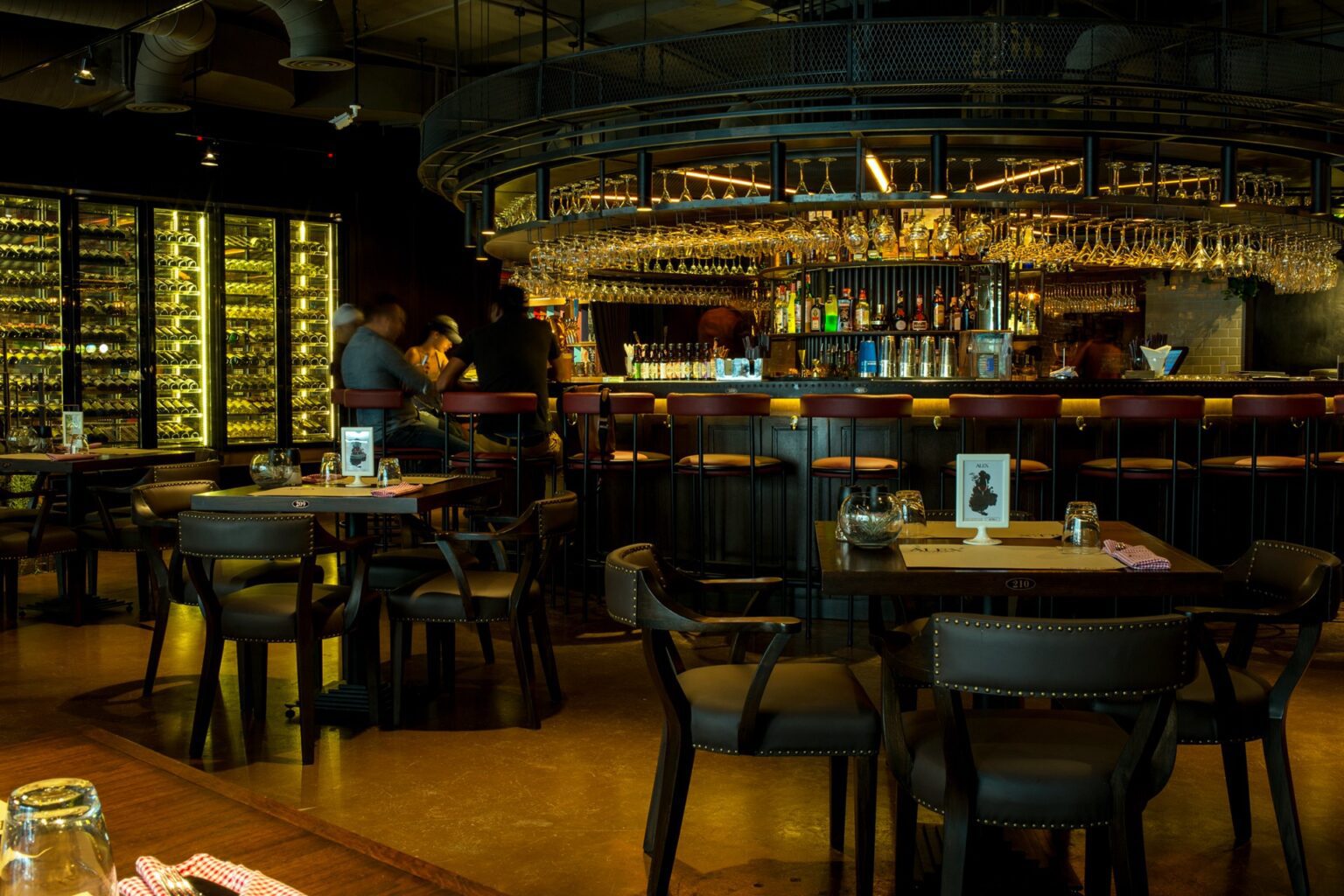 Interior of a restaurant showcasing tables and chairs, complemented by a renovated bar filled with an array of bottles