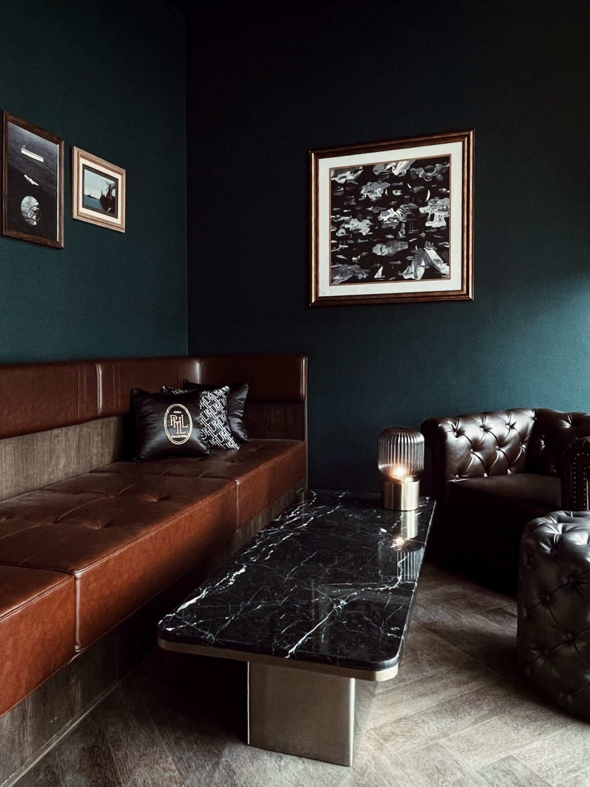 A dark green room featuring leather couches and a coffee table, showcasing the renovated Phill Collection lounge.