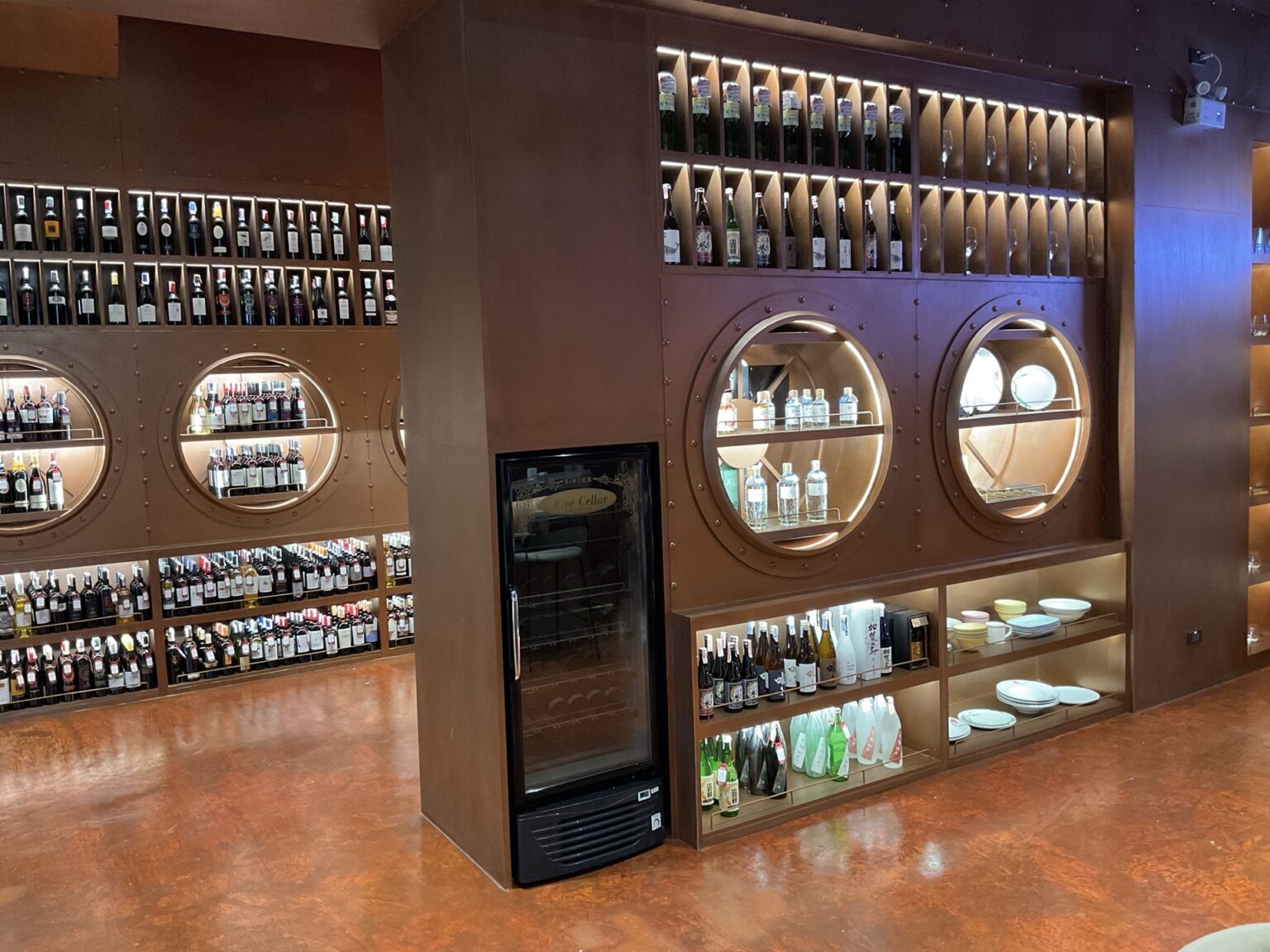 A stylish wine bar in a renovated cellar, showcasing shelves filled with an array of wine bottles against a rustic backdrop