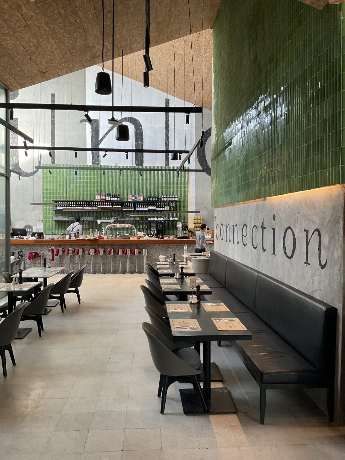 Interior of a renovated wine connection restaurant featuring green walls, tables, and an open kitchen design