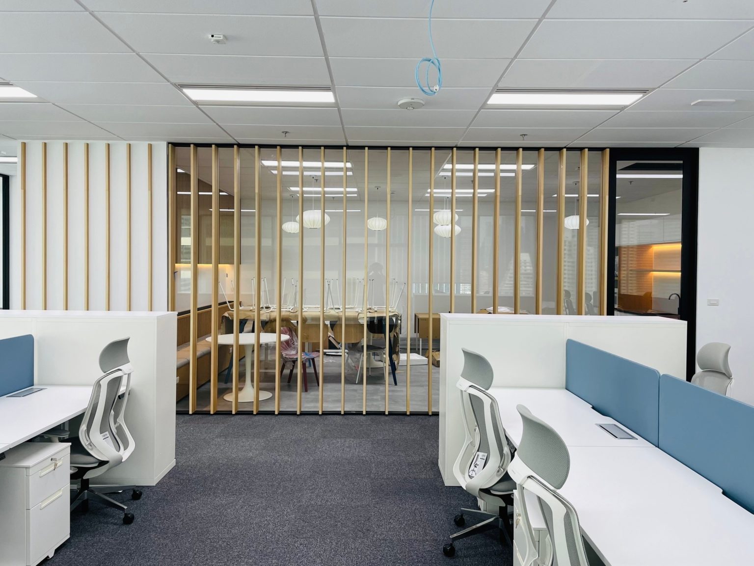 A modern open-space office featuring desks and chairs, showcasing renovated carpentry and a contemporary design.