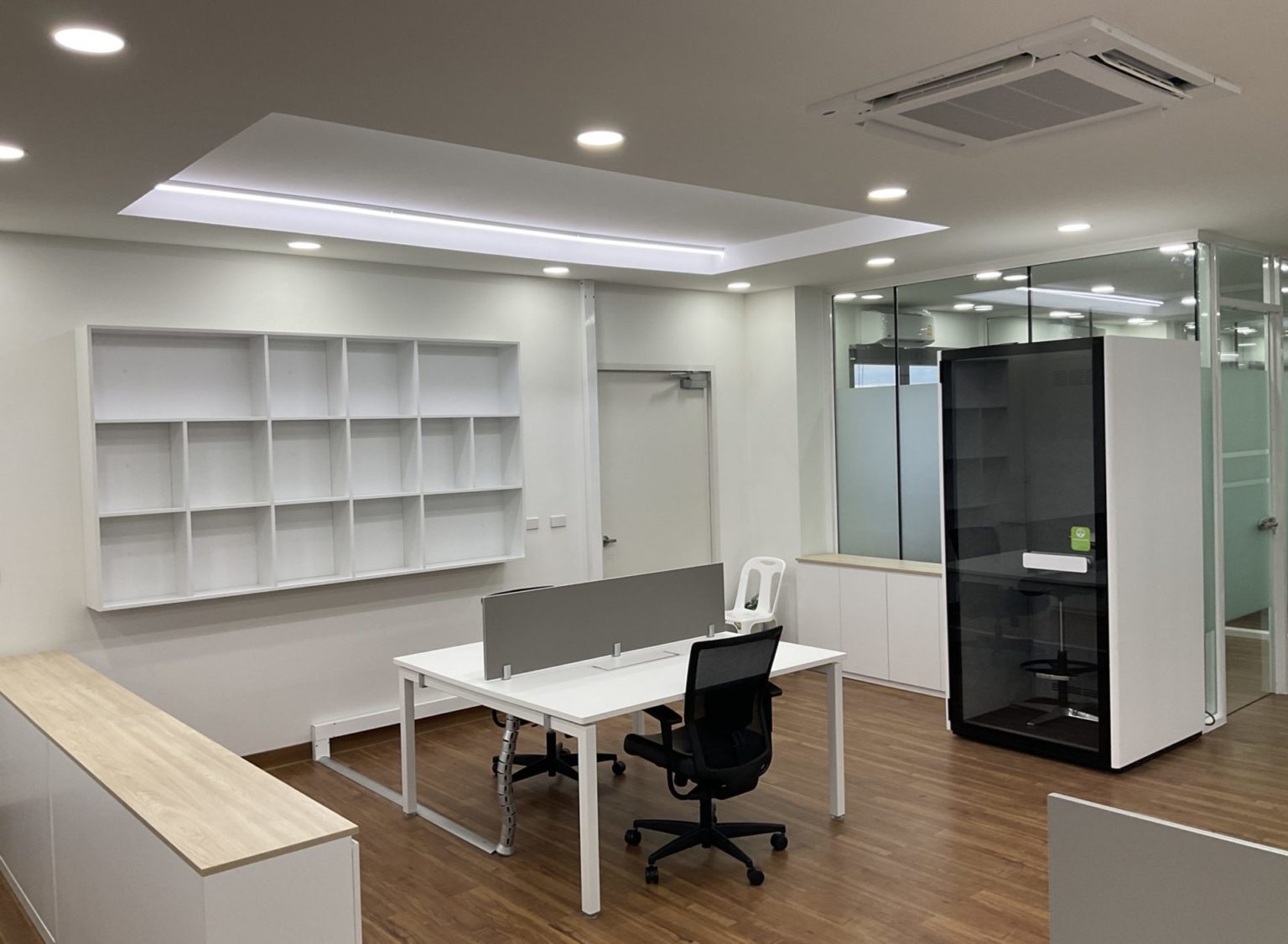 A renovated office featuring white walls and polished wooden floors, creating a bright and clean workspace.