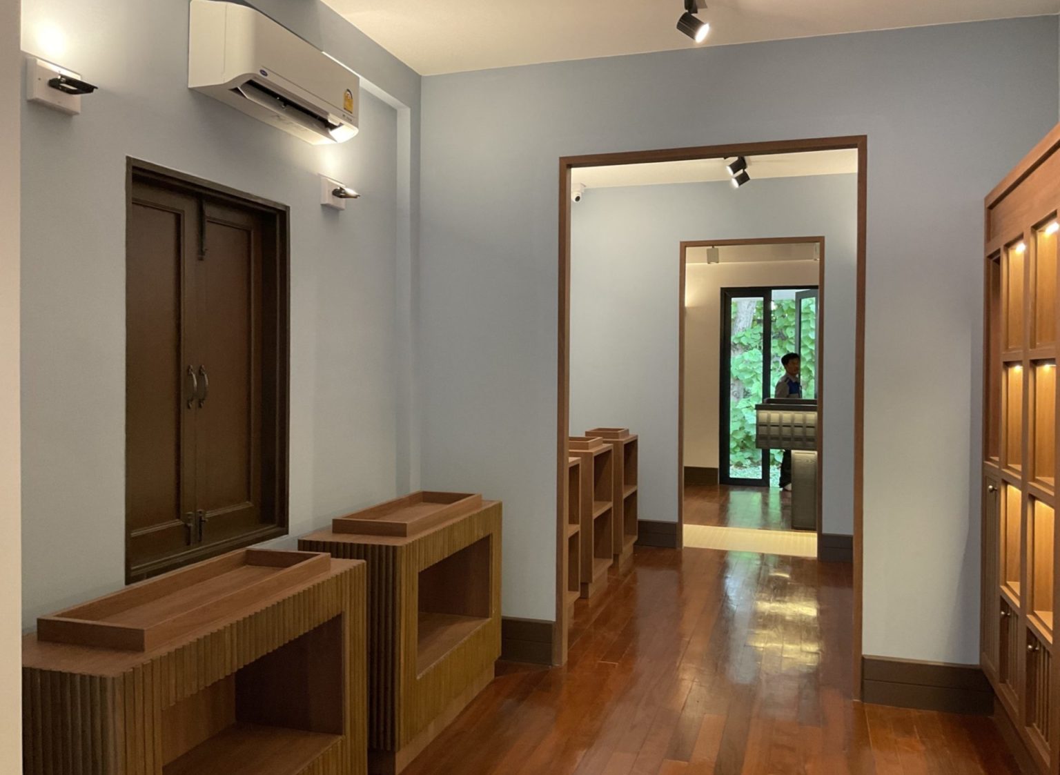 A renovated Italian wine showroom featuring a hallway with polished wooden floors and an elegant door.