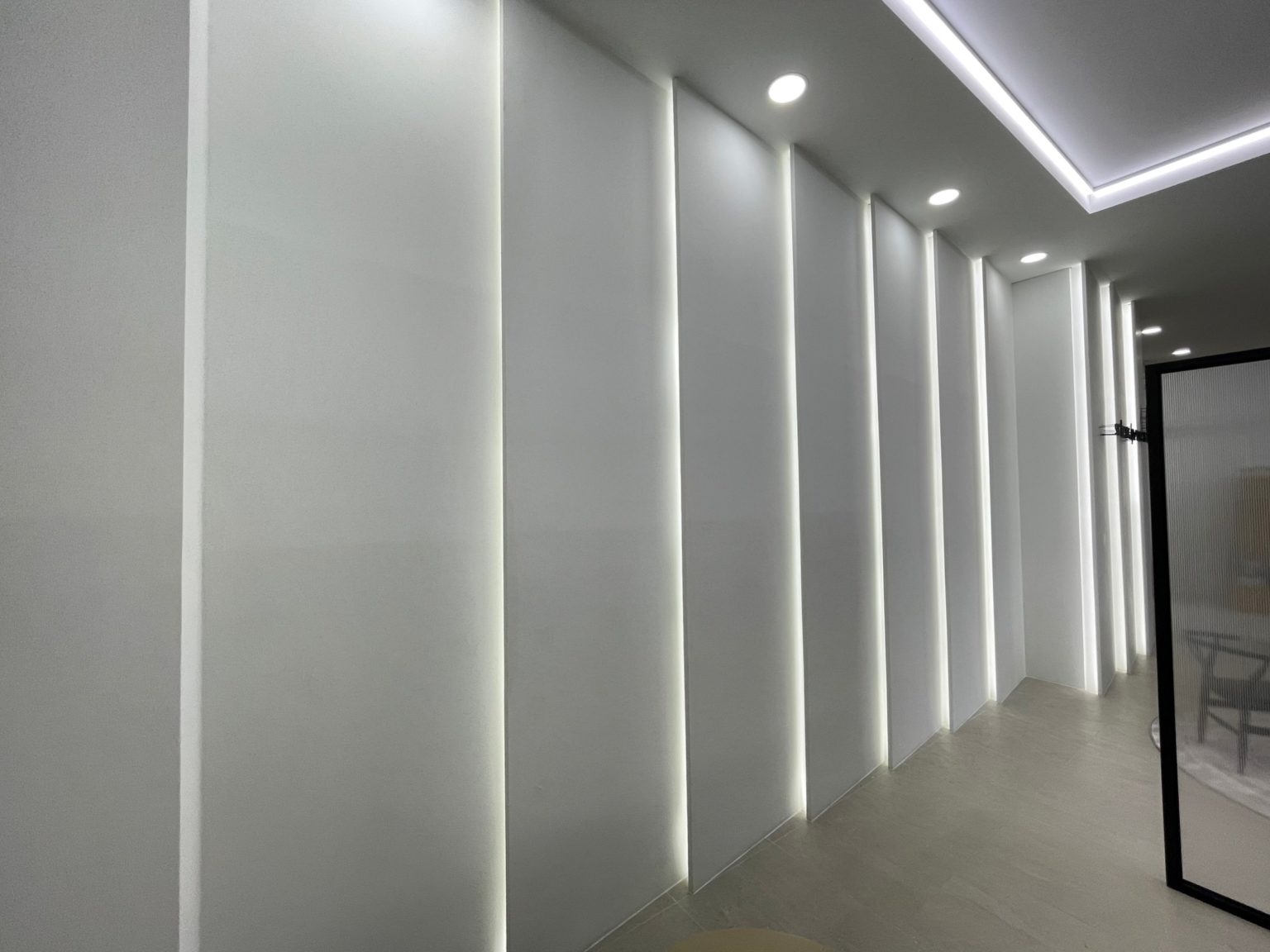 A renovated office featuring a white wall adorned with decorative lights, creating a bright and inviting atmosphere.