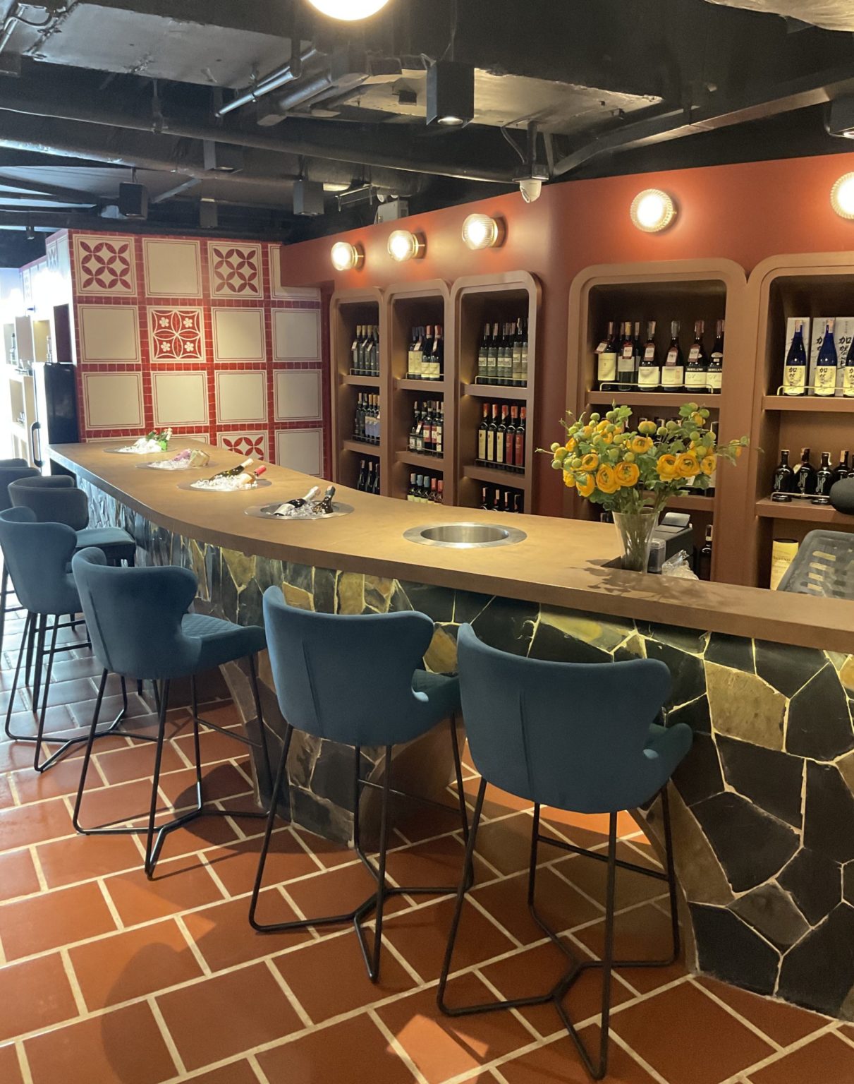 Interior of a renovated Italian restaurant bar with chairs and a table positioned in front of a decorative wall.