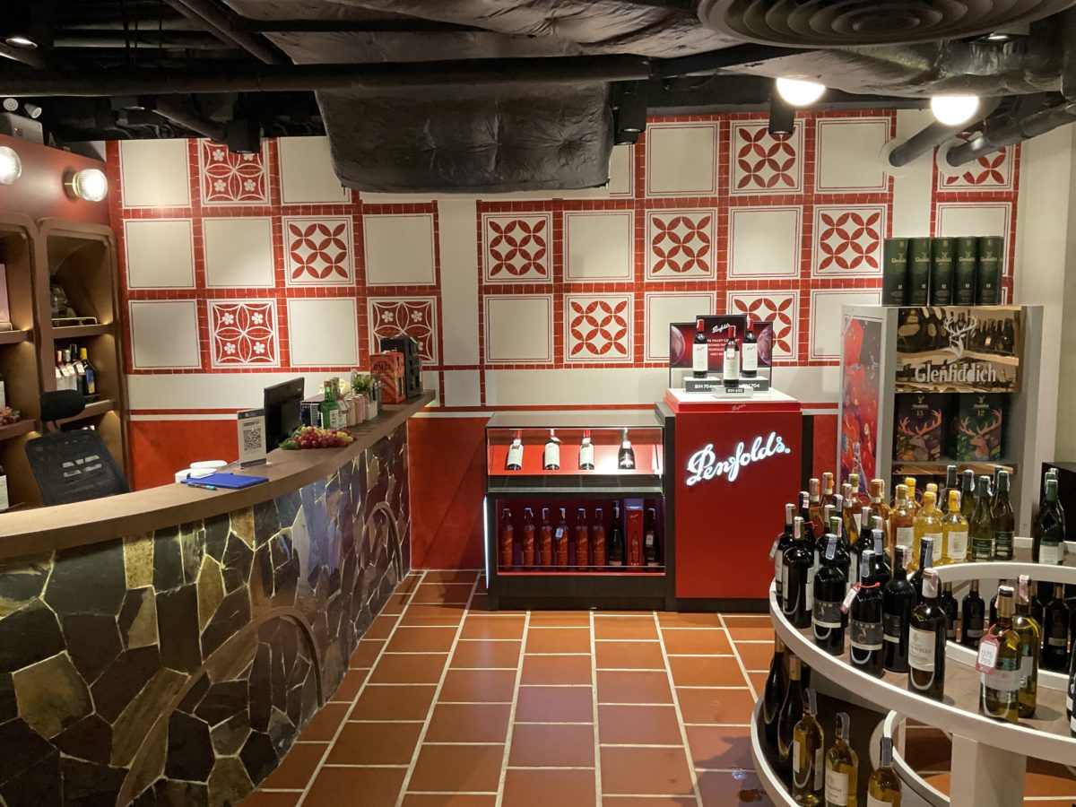 A wine shop featuring a red and white tiled floor, showcasing a selection of fine wines in a renovated Italian restaurant setting.