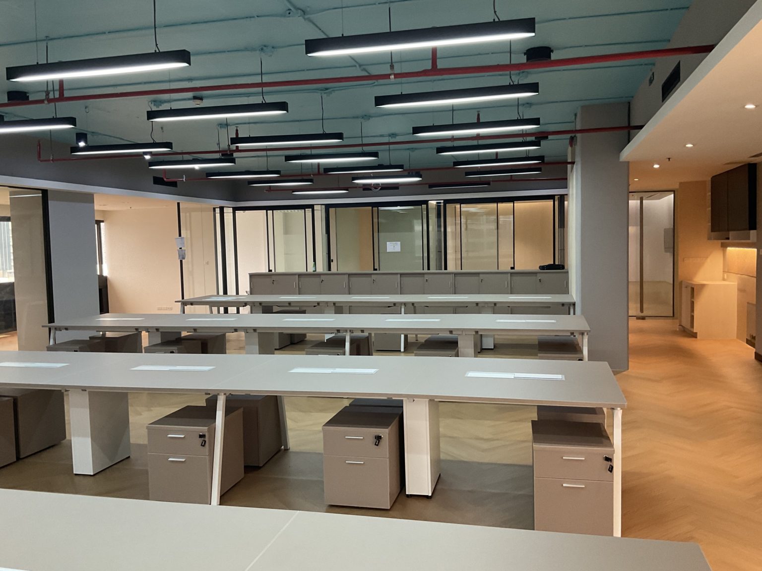 An empty, renovated office space with sleek desks and tables, highlighting a minimalist and professional environment