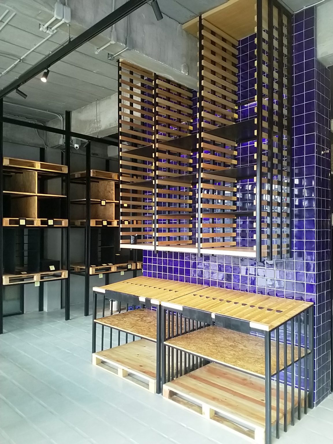 A wine rack displayed in a retail wine shop featuring renovated interiors with elegant blue tiles.