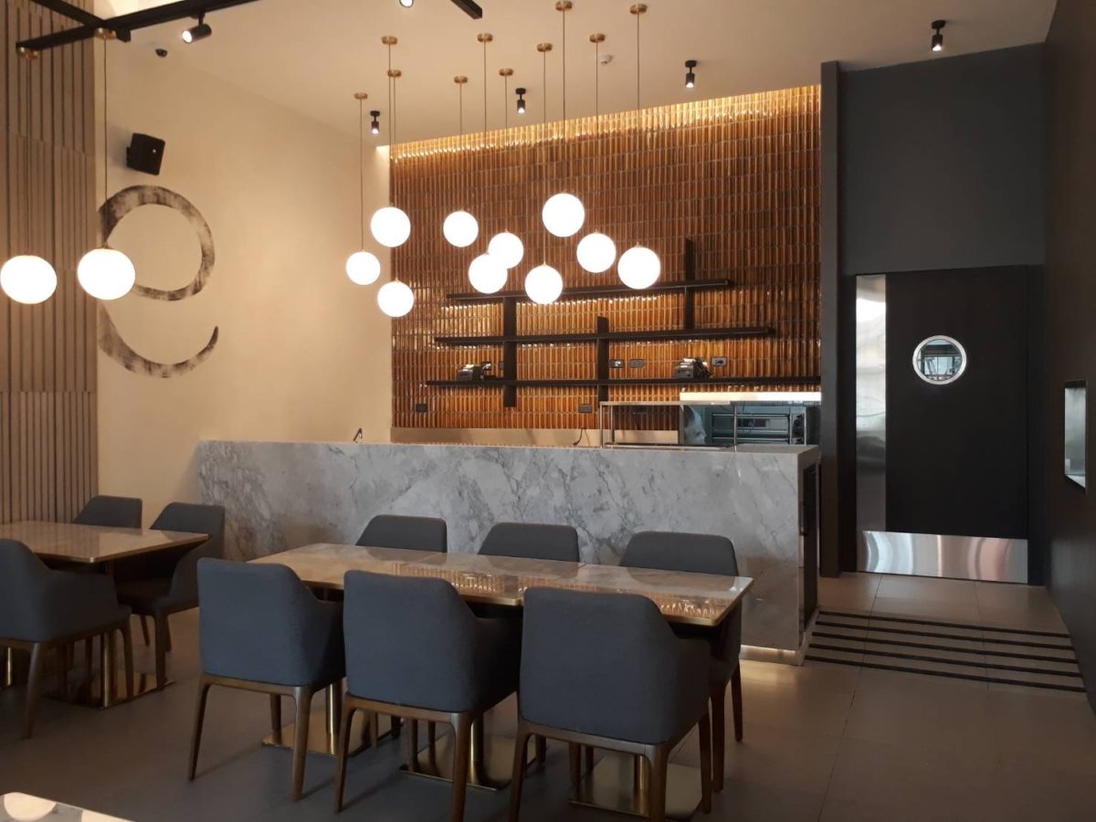 Interior of a renovated Italian restaurant showcasing a stylish marble counter and contemporary seating arrangements.