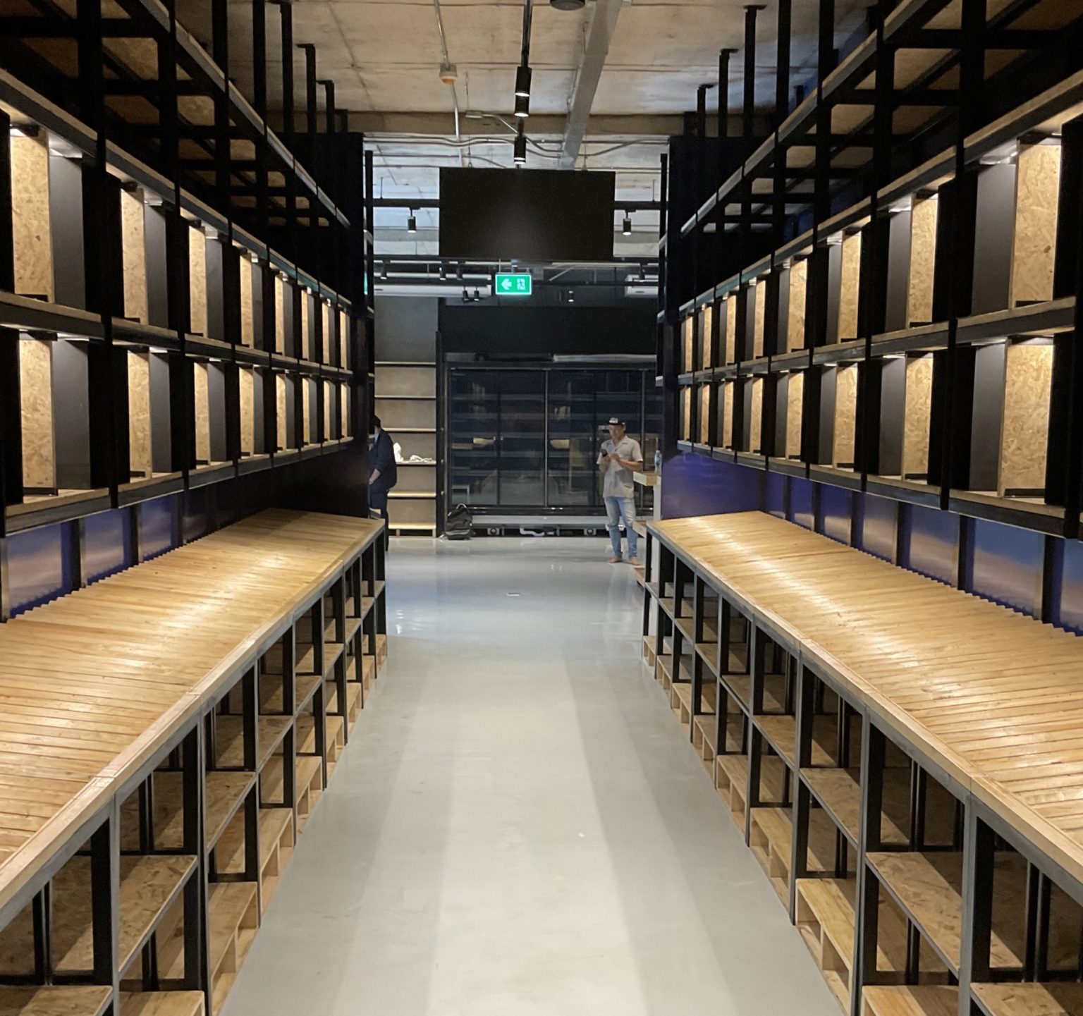 A renovated retail wine shop featuring a long row of shelves filled with various wine bottles in a spacious warehouse setting.