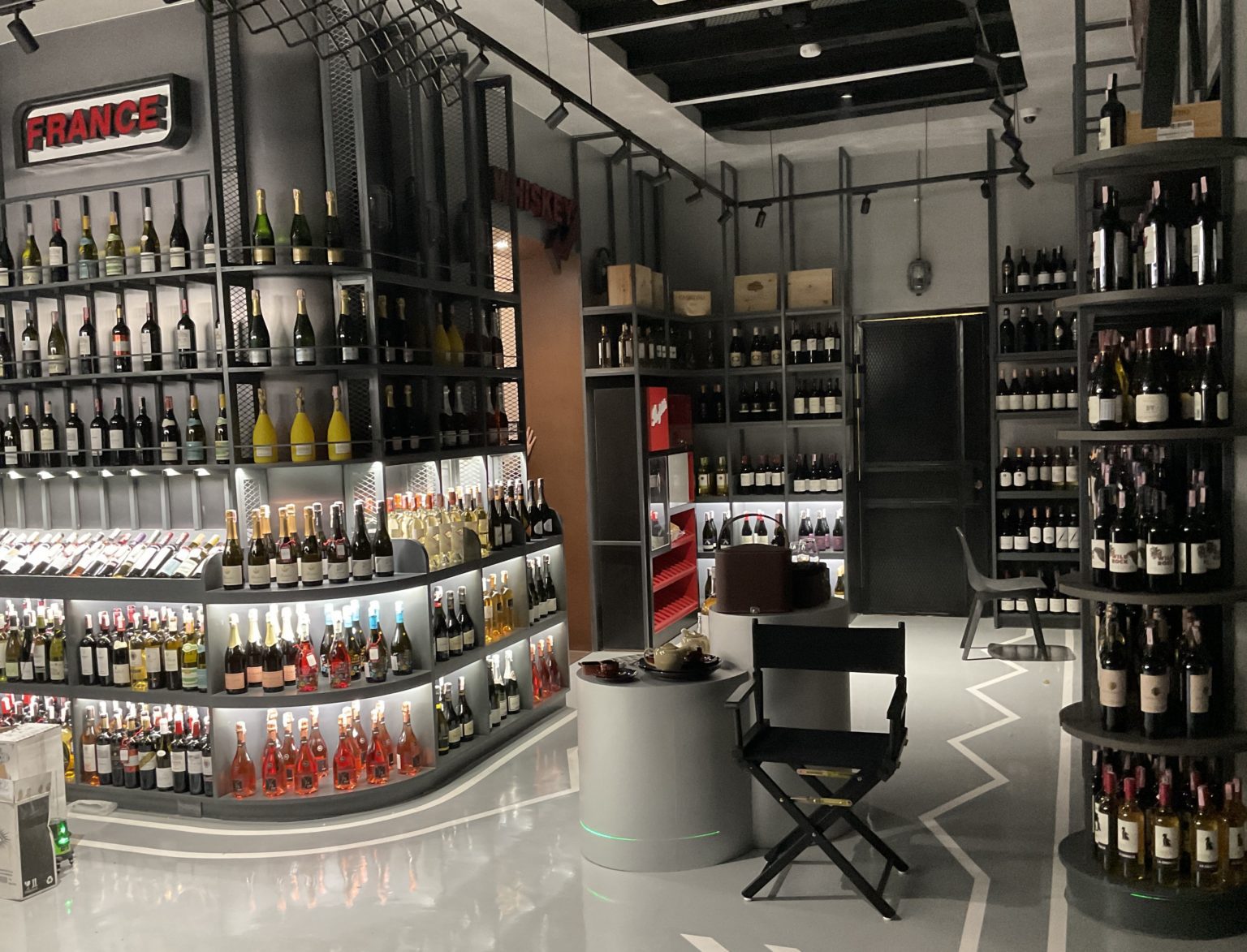 Interior of a renovated Italian wine store showcasing shelves inspired by a race circuit design, brimming with various wine bottles