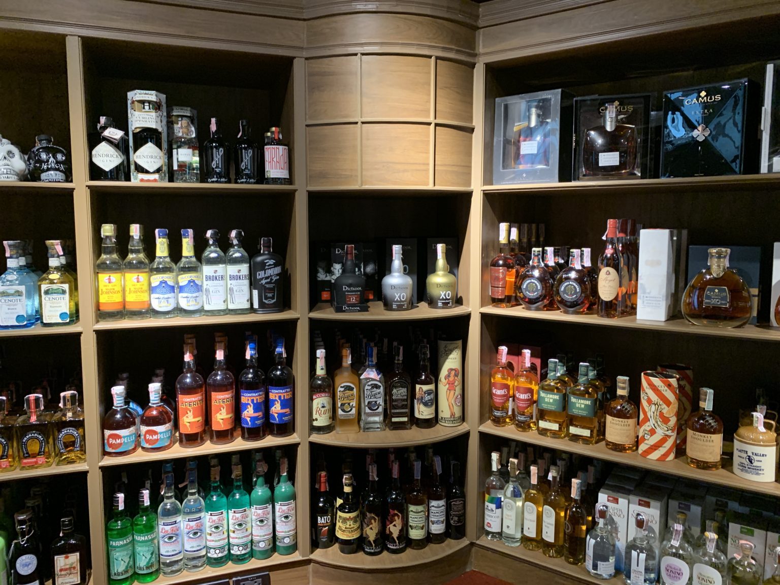 A renovated Italian wine showroom featuring a shelf adorned with an array of liquor bottles, showcasing diverse selections.