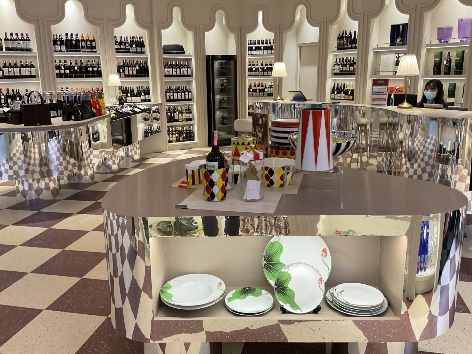 A renovated Italian wine showroom featuring an extensive display of wine bottles and elegant plates.