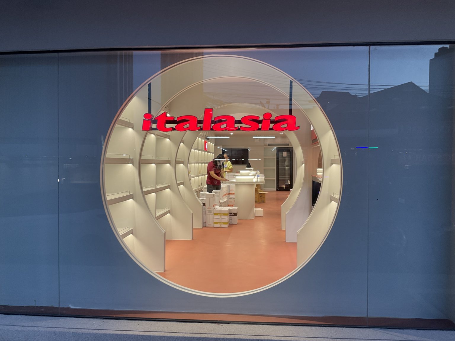 A renovated Italian wine showroom featuring a large round window in its store display, showcasing elegant wine bottles.