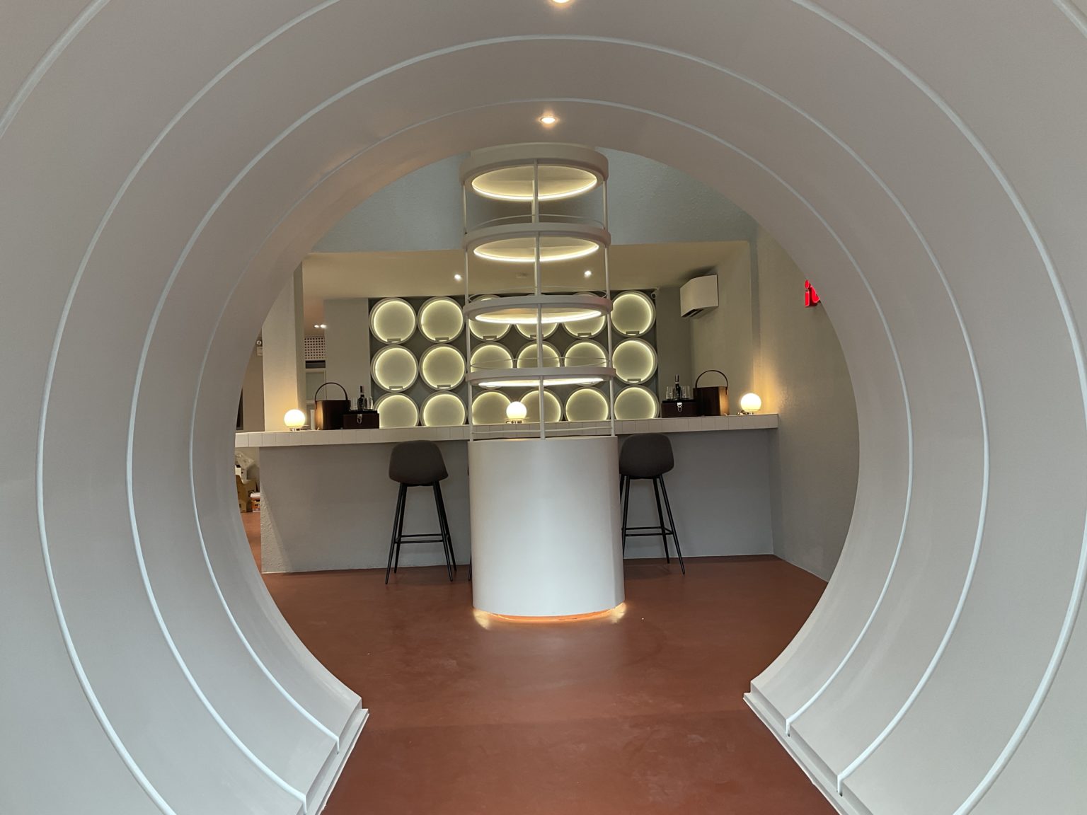 Interior of a renovated Italian wine showroom showcasing a circular bar at the center, surrounded by stylish wine displays.