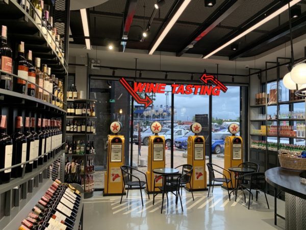 A renovated Italian wine showroom featuring modern design elements and showcasing various wine bottles and barrels.