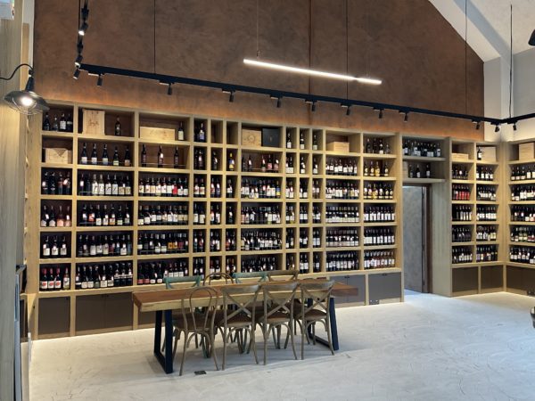 Interior of a renovated Italian wine store showcasing numerous wine bottles elegantly arranged on shelves.