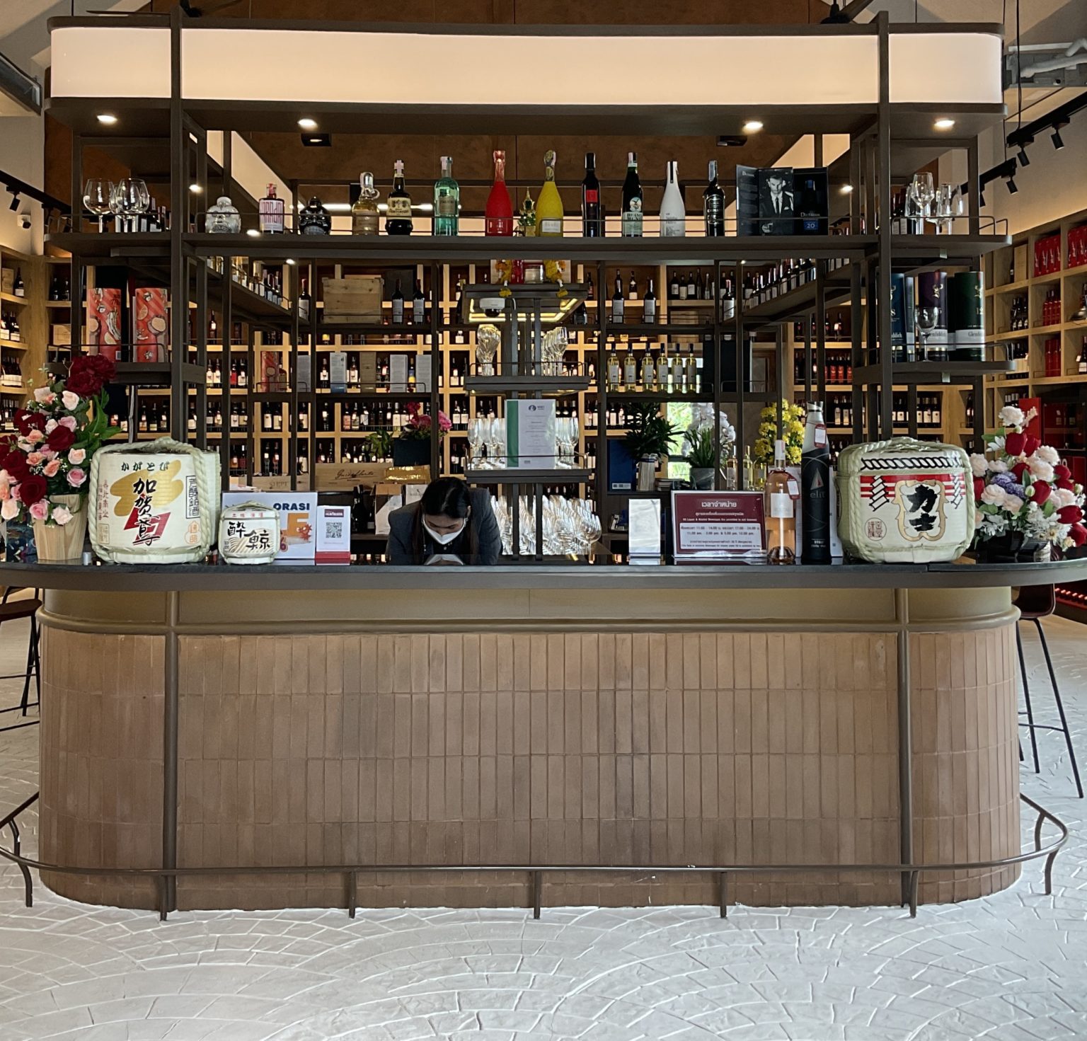 A stylish Italian wine showroom with a large wooden counter and inviting chairs, perfect for wine tasting experiences.