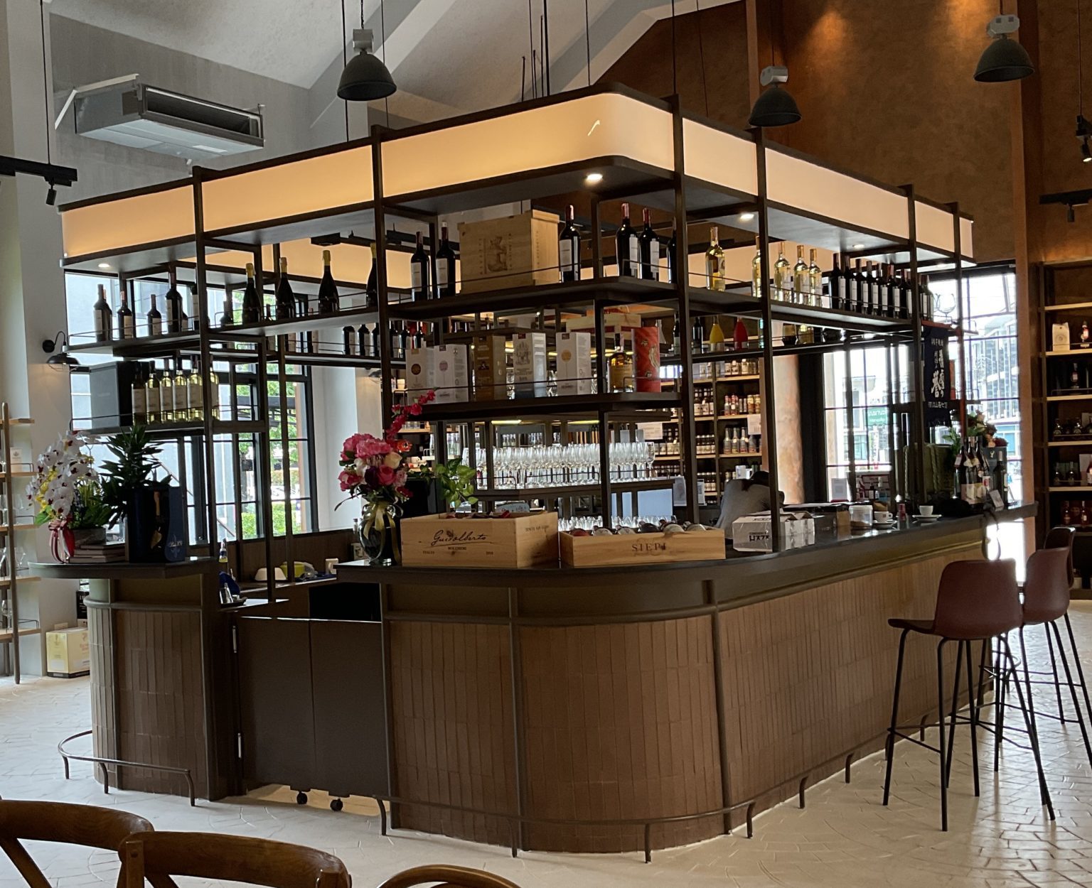 Interior of a renovated Italian wine showroom showcasing a large wooden bar counter complemented by stylish seating.