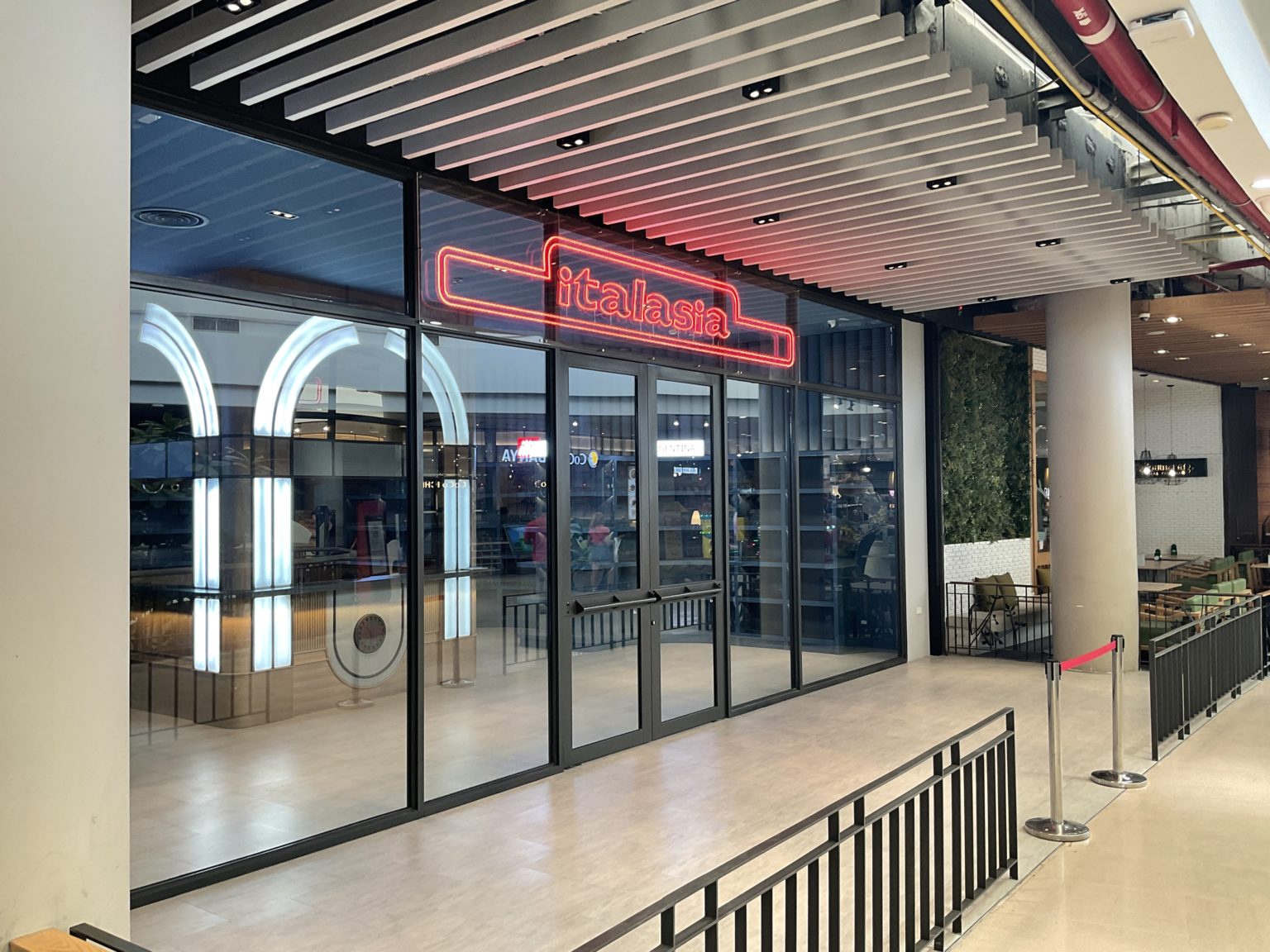 A renovated Italian wine showroom featuring a restaurant entrance adorned with a vibrant red neon sign on the door.