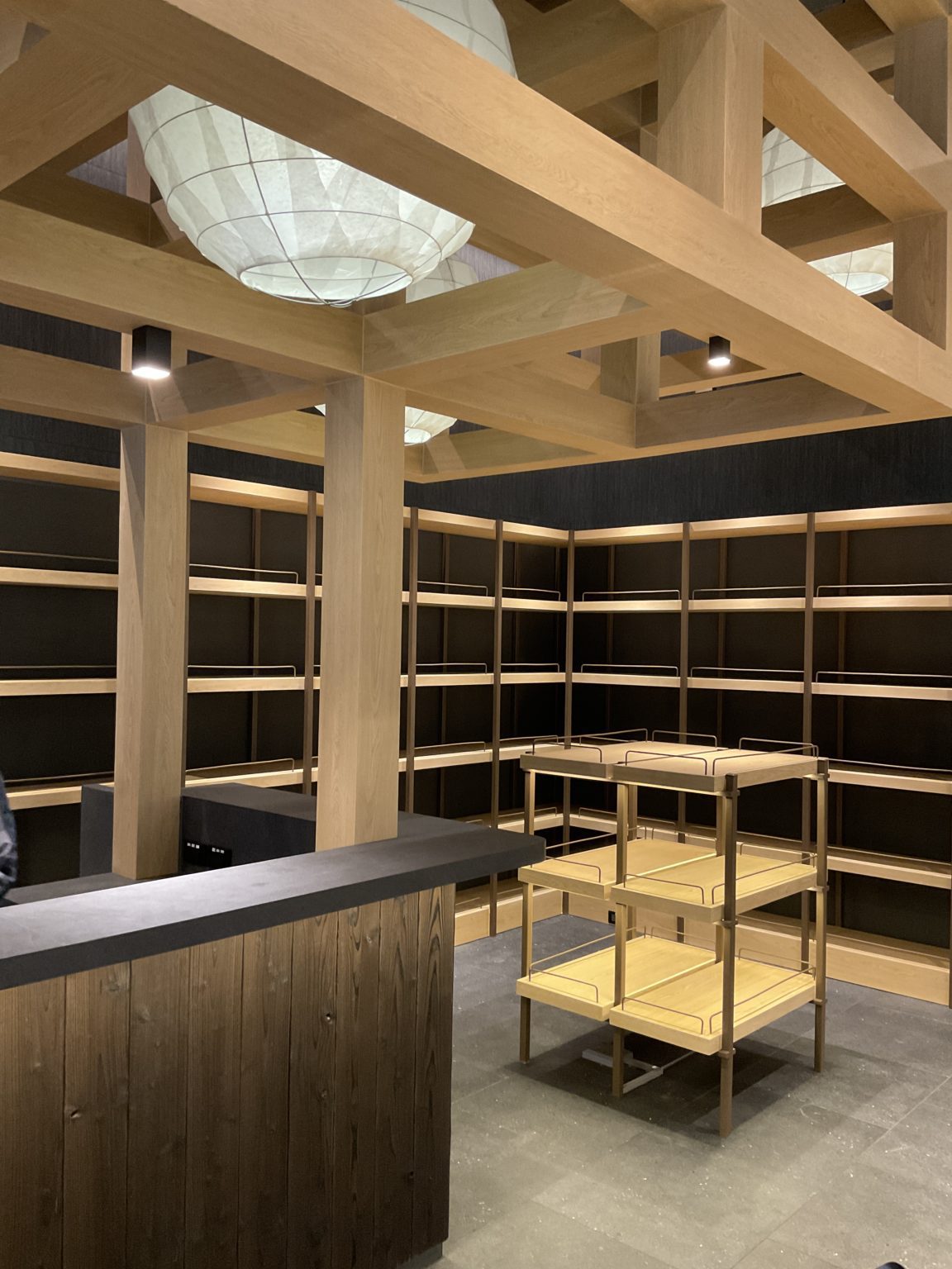 Interior of a renovated Italian wine showroom with elegant wooden shelves and a sleek counter, highlighting fine carpentry.