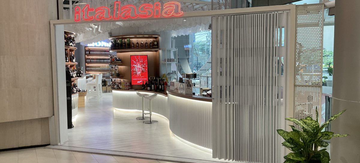 A modern shopping mall featuring a large glass door, showcasing a renovated Italian wine showroom inside.