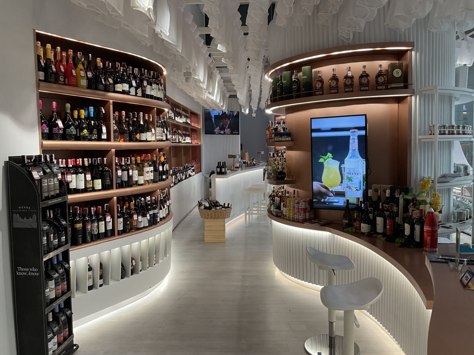 A renovated Italian wine showroom featuring a bar with an extensive selection of alcohol and gourmet food options.