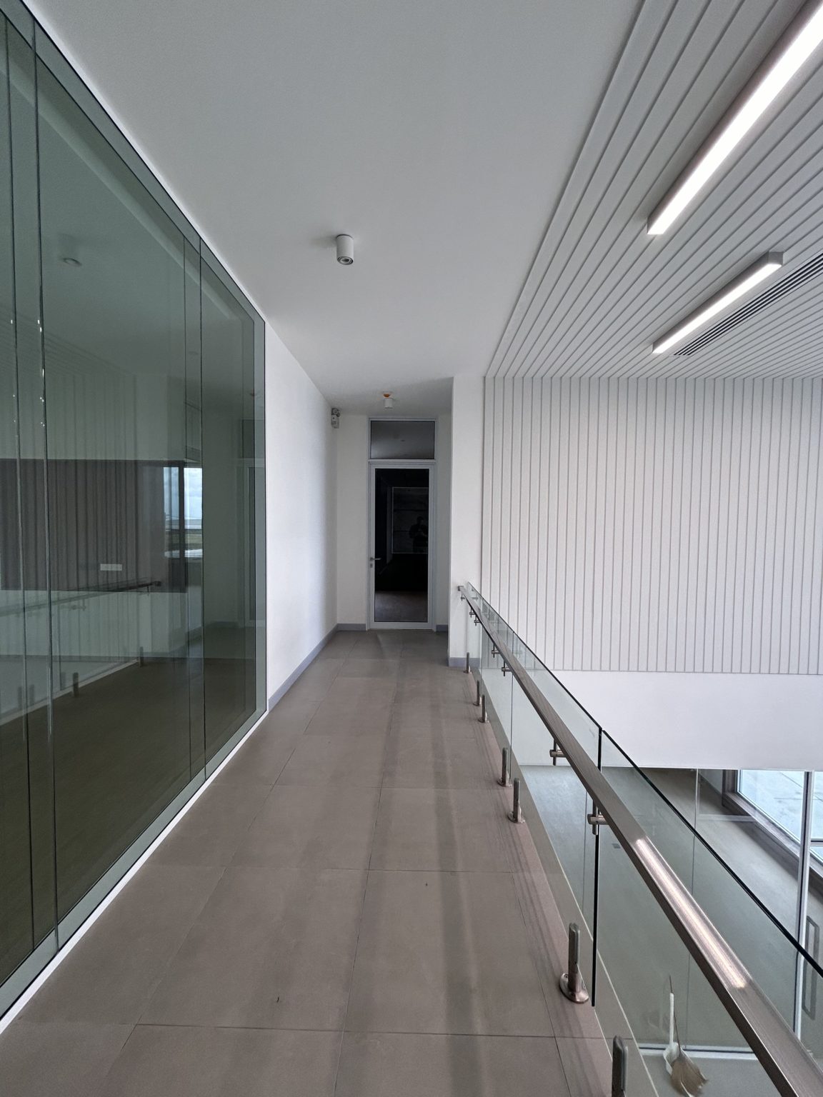 A long hallway featuring transparent glass walls creating an open and airy atmosphere.