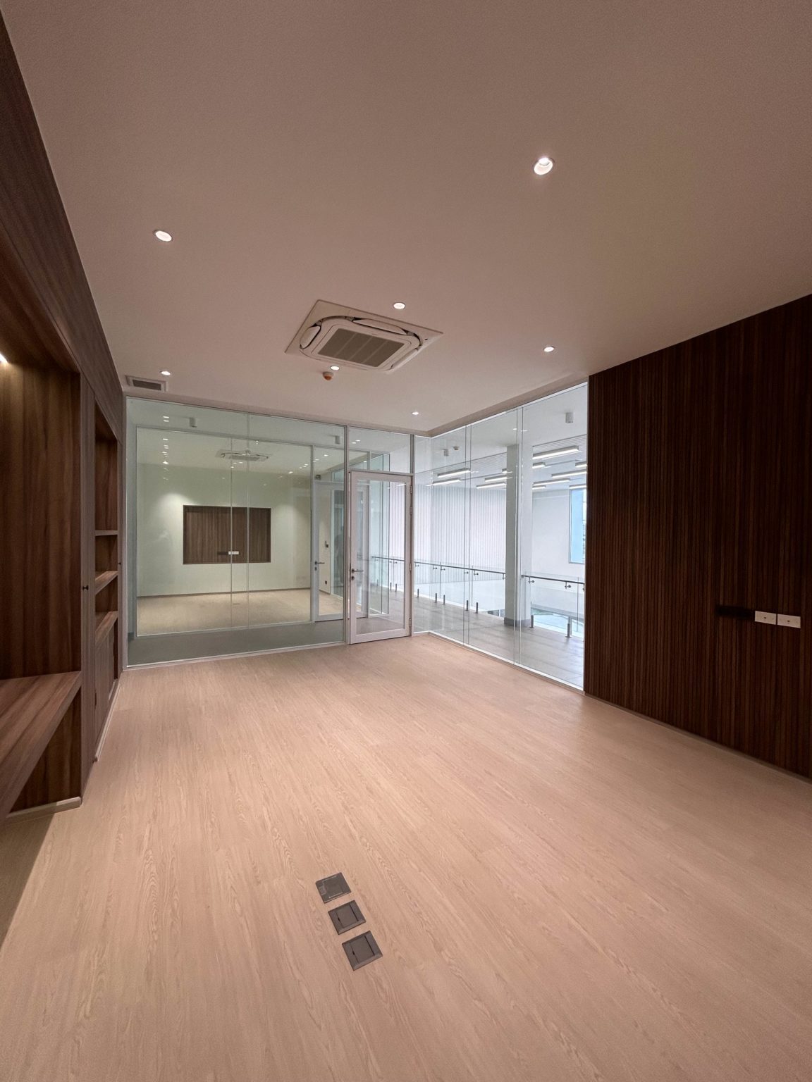 A contemporary office featuring wooden shelf and wall and glass doors.