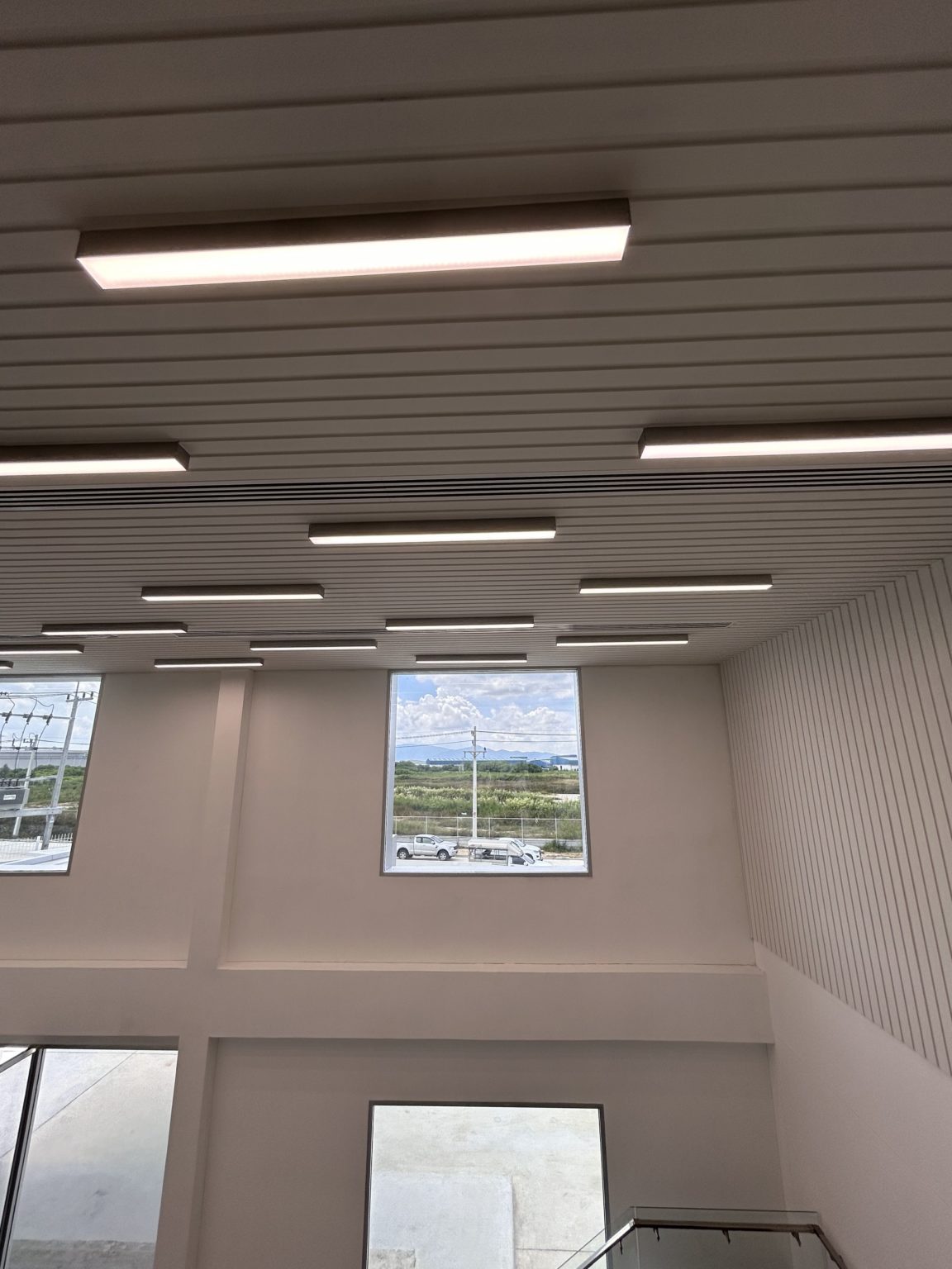 Large windows in a hall and white wooden ceiling which lighten up the room.